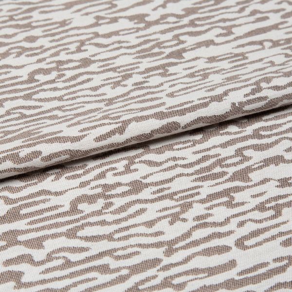 Decorative woven fabric with white and light beige abstract zebra-like pattern, tightly woven and folded across the center; lying as a layered textile sample in a close-up, evenly lit shot.