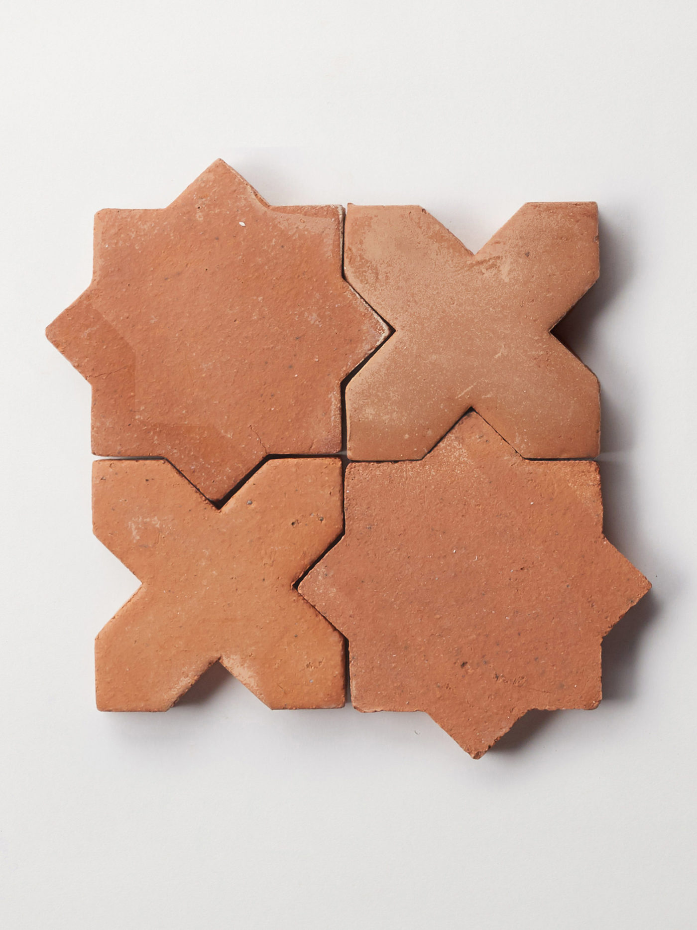 a set of four red terracotta tiles on a white surface.