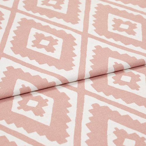 Woven pink-and-white geometric fabric with repeating diamond/tribal motifs, partially folded to show texture; photographed close-up on a neutral surface under soft, even studio lighting.