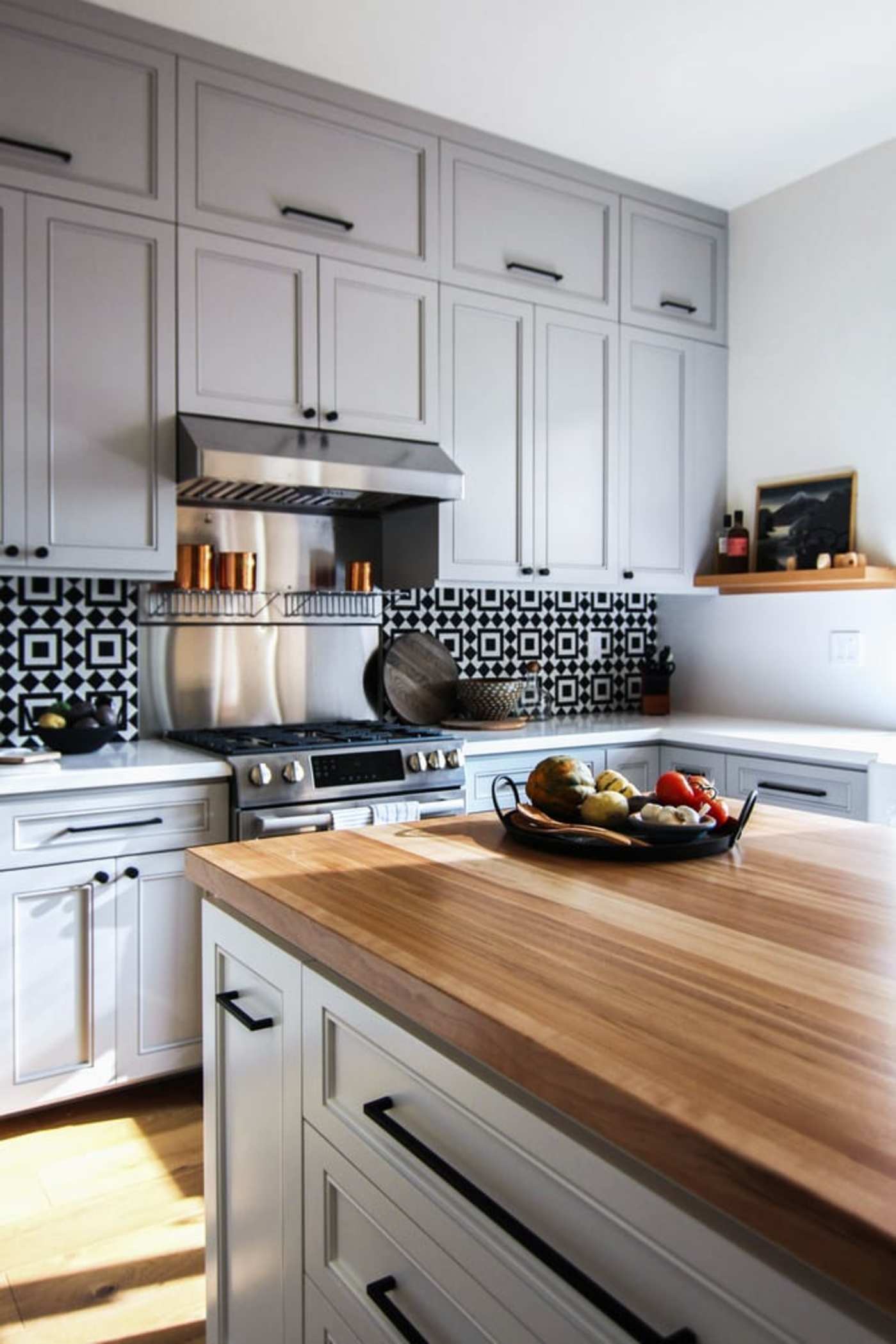 a kitchen with gray cabinets and a wooden counter top.