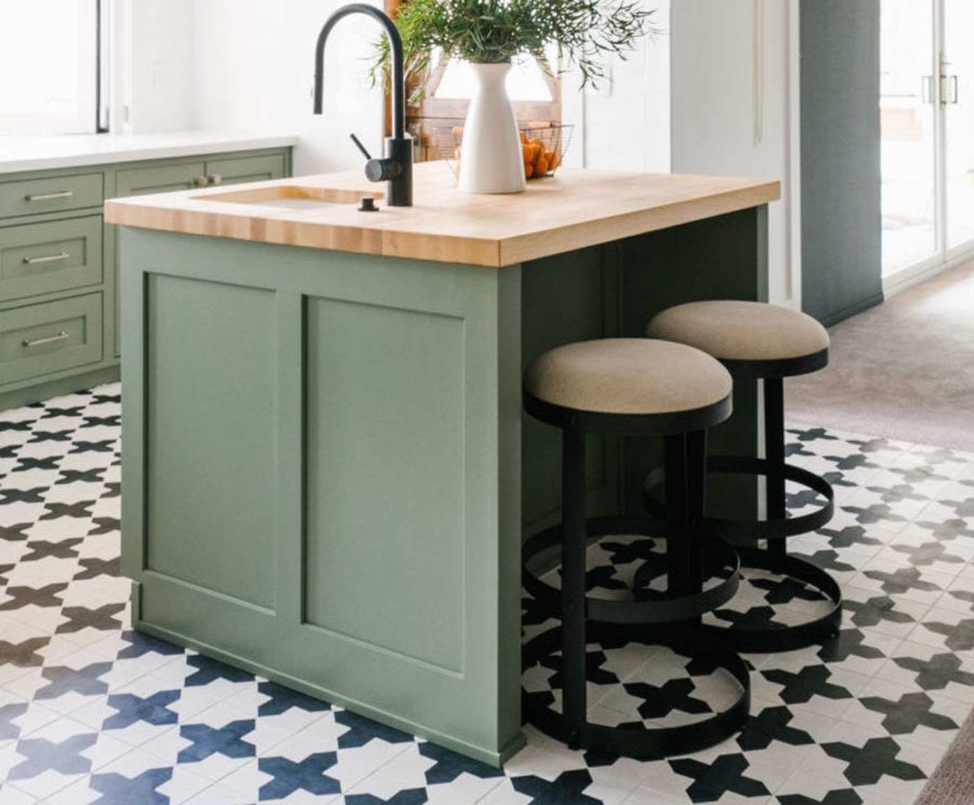 a kitchen with a green island and black and white tile.