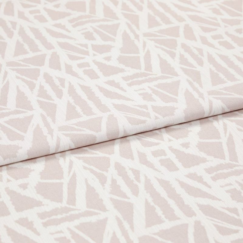 Pale pink woven fabric with white abstract angular lines (object), folded over itself (action), shown in a studio-lit close-up highlighting the textile’s texture and overlapping layer (context).
