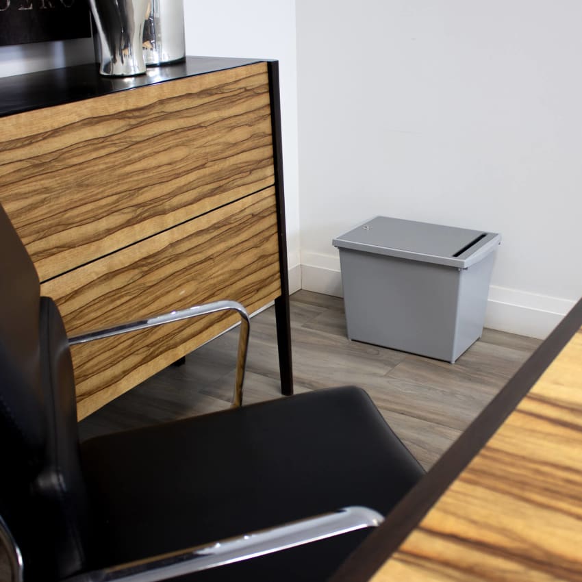 grey container for collecting personal documents with a lockable lid sitting on the floor in a meeting room