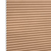 Beige honeycomb (cellular) blind with visible white cell ends at left, closed and blocking light; close-up product shot against a plain white background with even lighting.