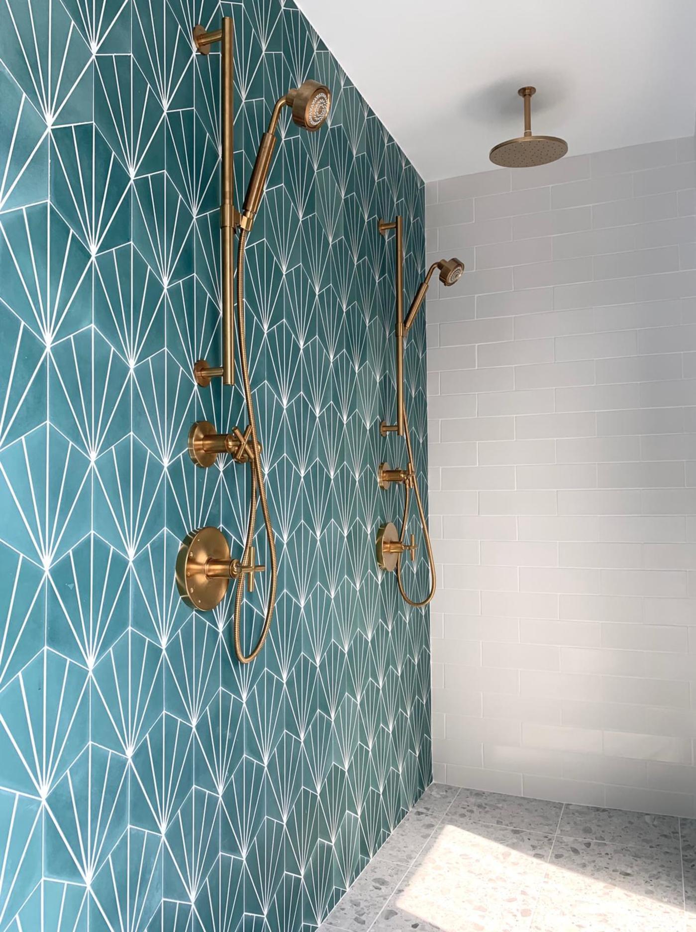 a bathroom with a blue tiled wall and brass fixtures.