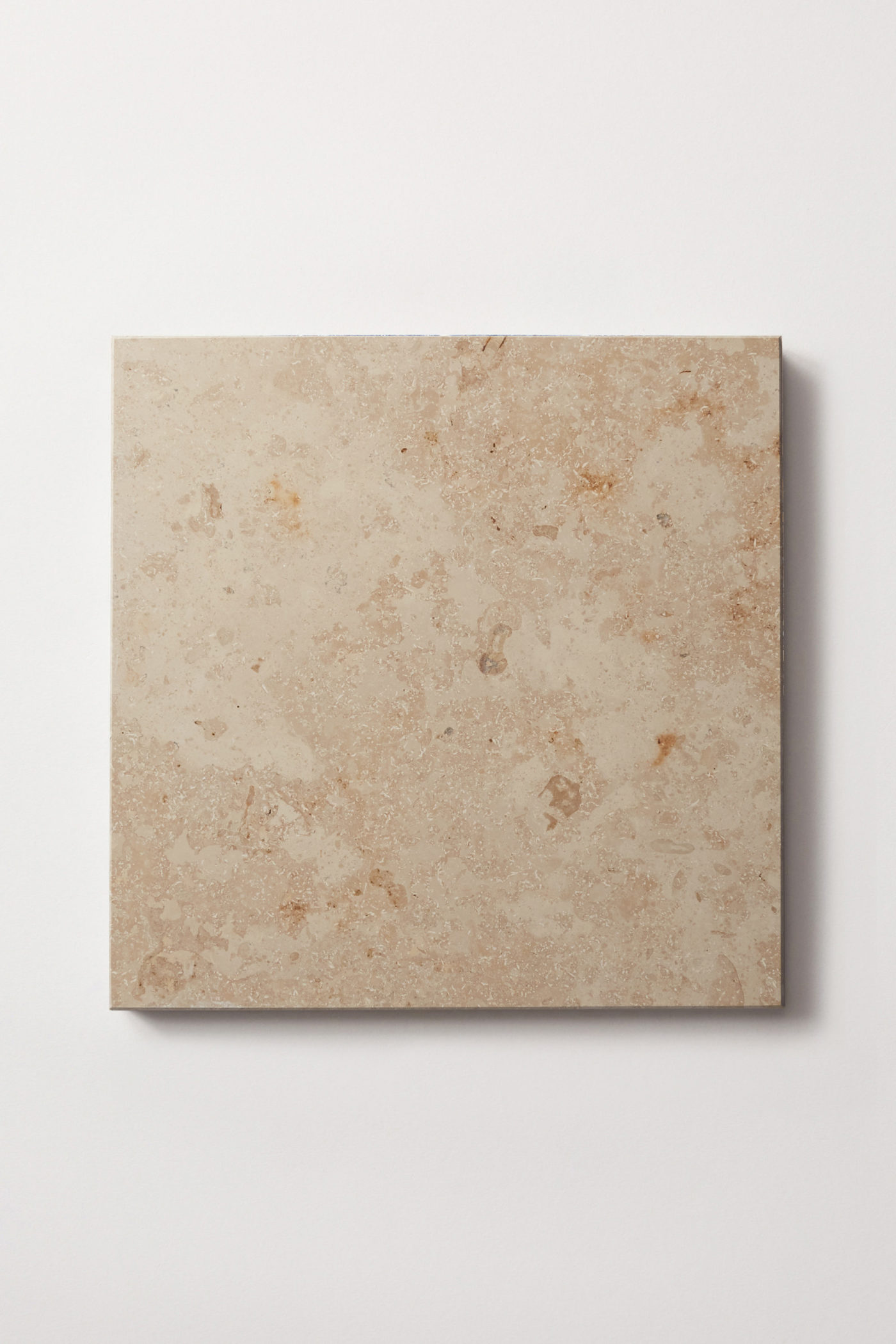 a square limestone tile on a white surface.