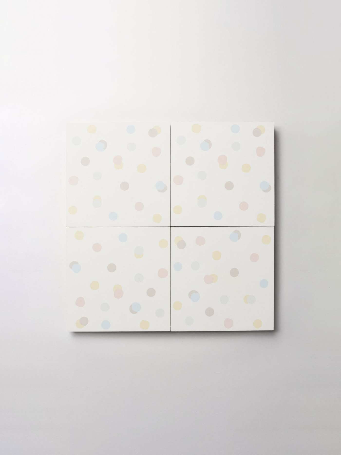 four white tiles with multicolored polka dots on a white background.