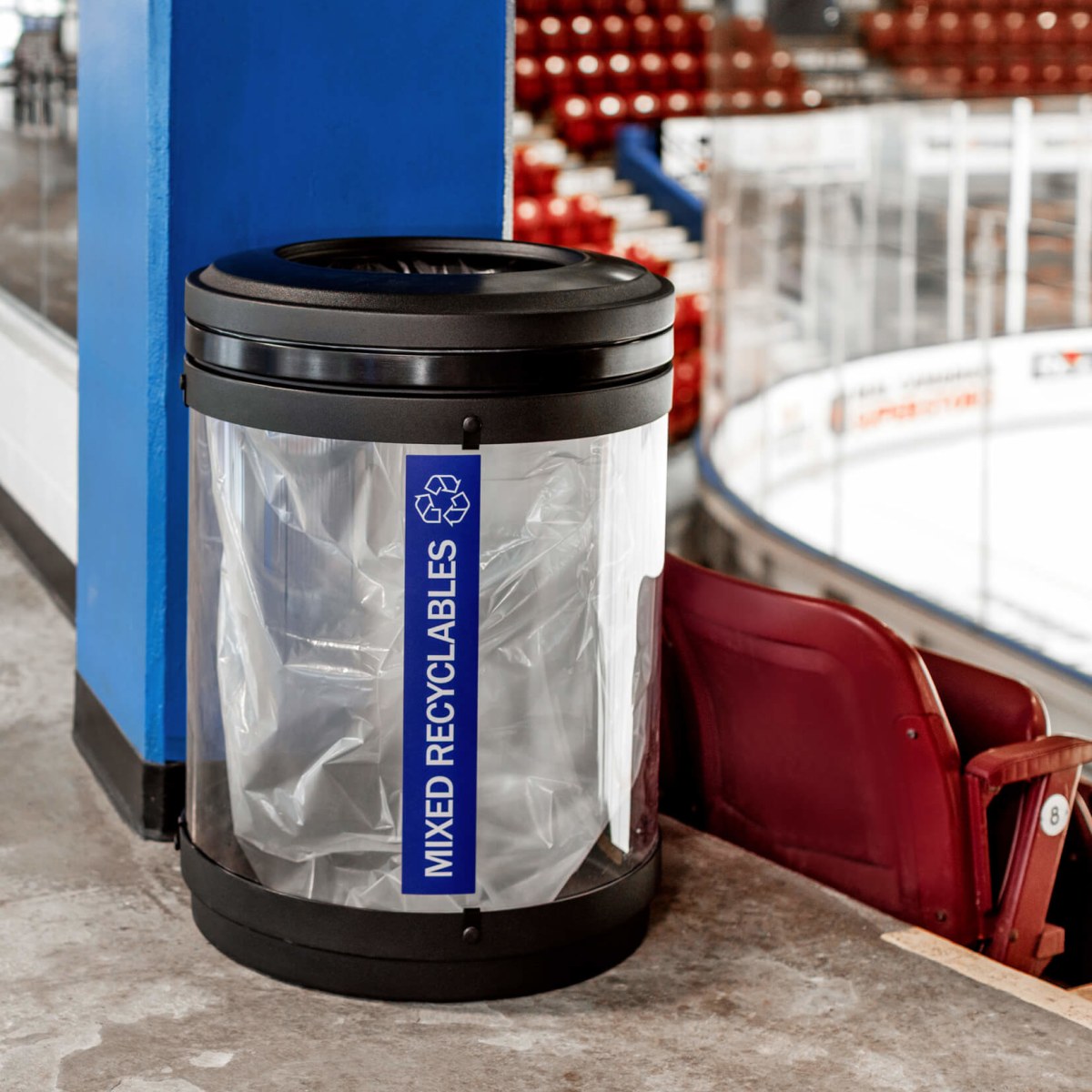 black and clear plastic recycling bin inside a hockey arena sitting beside seating