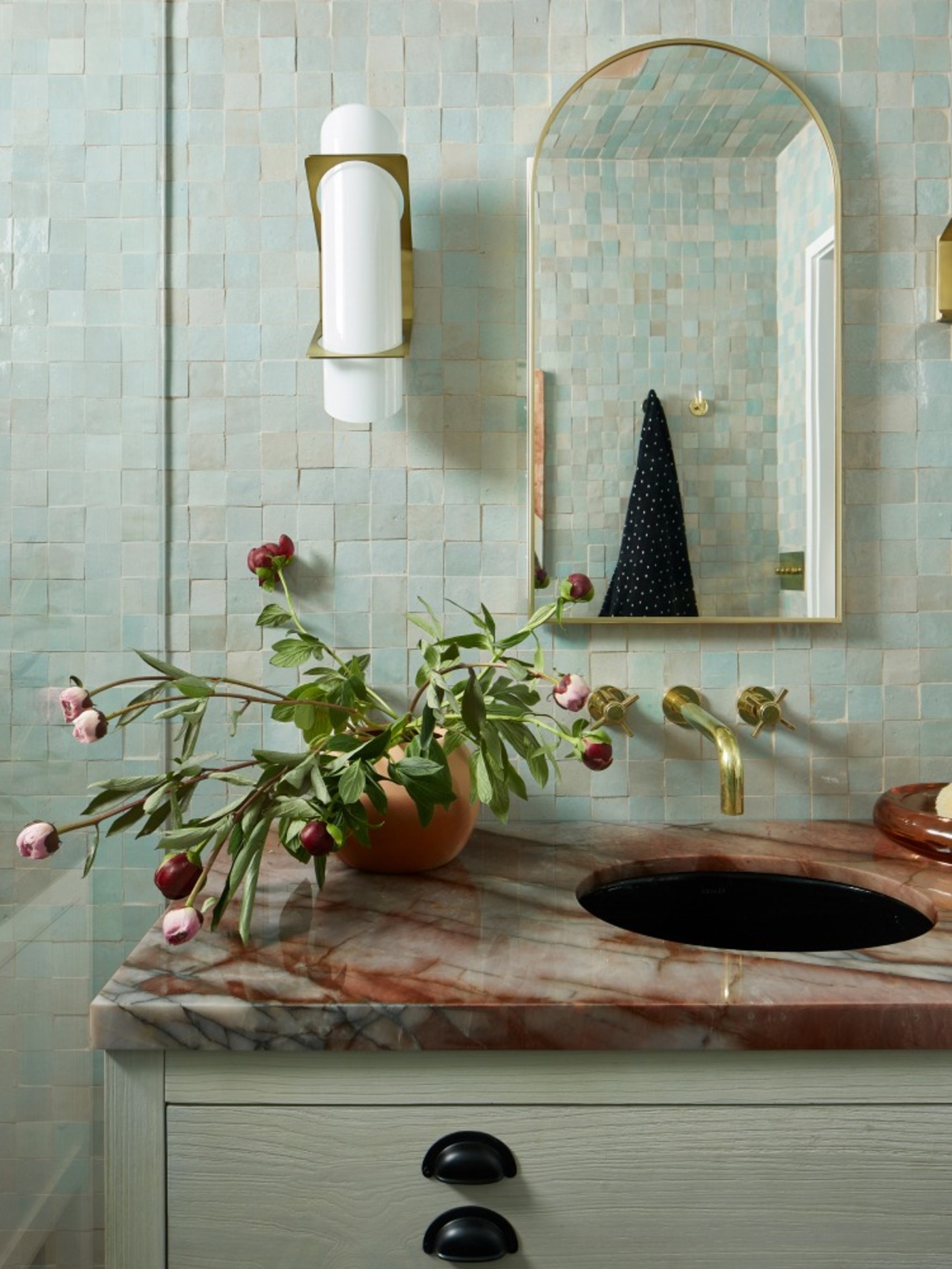 a bathroom with a green tiled backsplash wall.