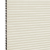 Cream cellular (honeycomb) blind with dark-lined cells visible on the left; closed into uniform horizontal pleats, filtering soft diffuse indoor light against a neutral background.
