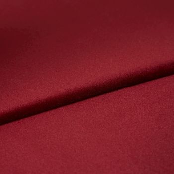Burgundy satin fabric, folded diagonally with a soft sheen and smooth texture; fold casts a subtle shadow, close-up on a flat surface under even studio lighting.