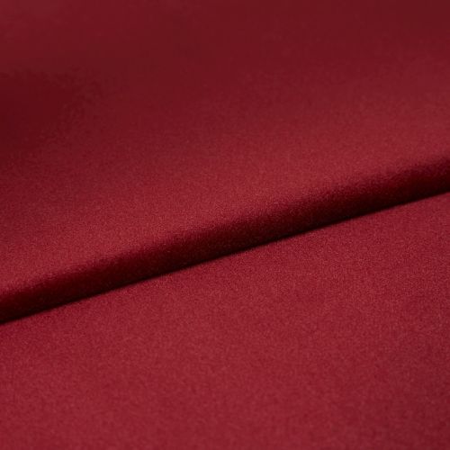 Burgundy satin fabric, folded diagonally with a soft sheen and smooth texture; fold casts a subtle shadow, close-up on a flat surface under even studio lighting.