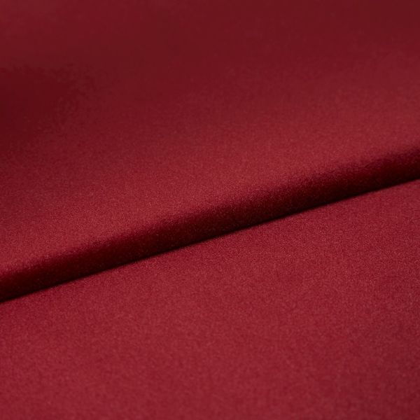 Burgundy satin fabric, folded diagonally with a soft sheen and smooth texture; fold casts a subtle shadow, close-up on a flat surface under even studio lighting.