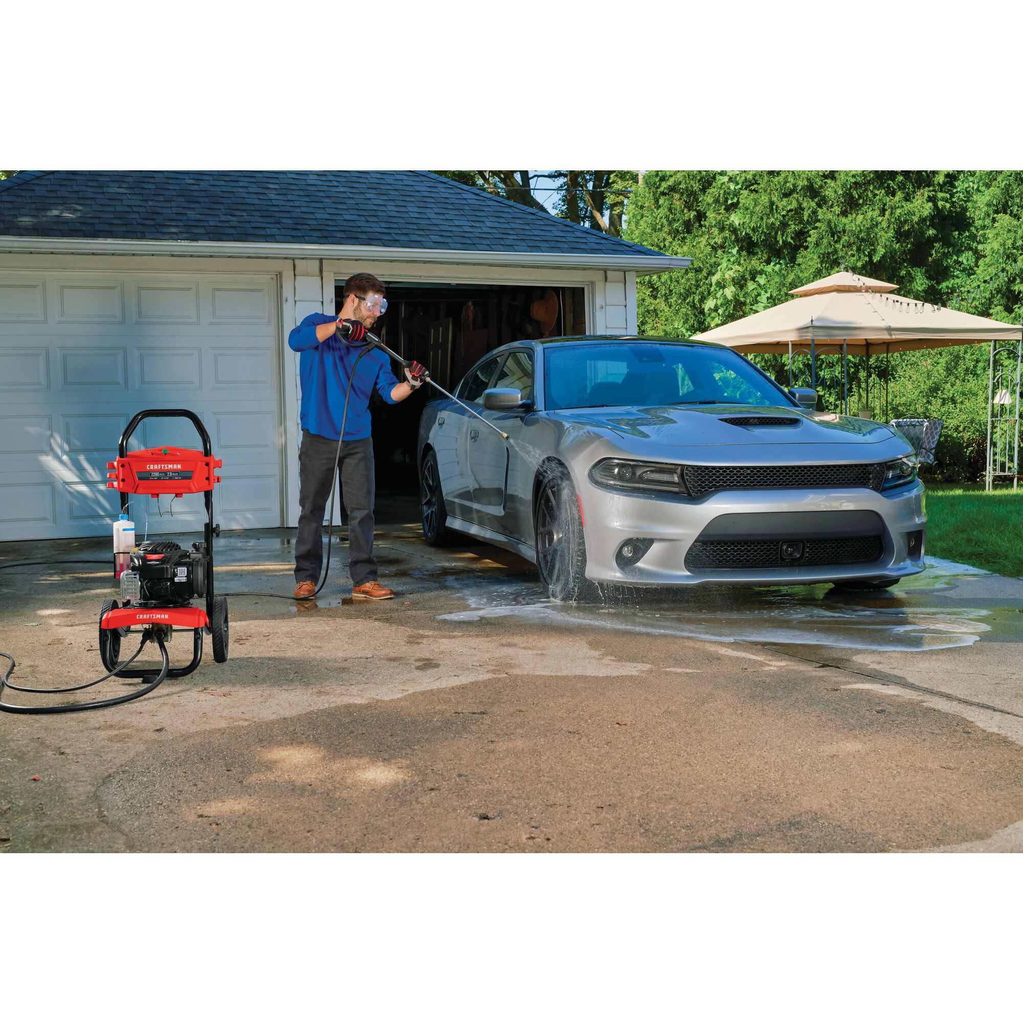 2200 MAX Pounds per Square Inch or 2 MAX Gallons Per Minute Pressure Washer being used by person to wash car tires outdoors.
