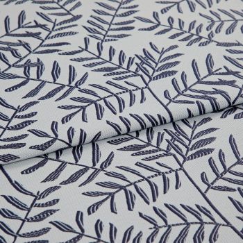 Light gray woven fabric with navy embroidered fern-like leaf pattern, folded in the center creating overlapping layers; close-up, soft diffuse lighting reveals textile texture and stitch detail.