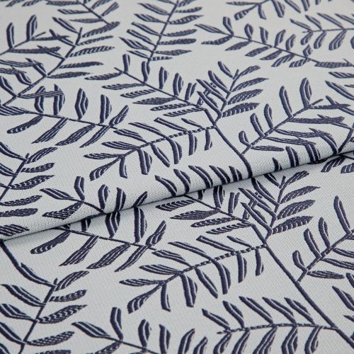 Light gray woven fabric with navy embroidered fern-like leaf pattern, folded in the center creating overlapping layers; close-up, soft diffuse lighting reveals textile texture and stitch detail.