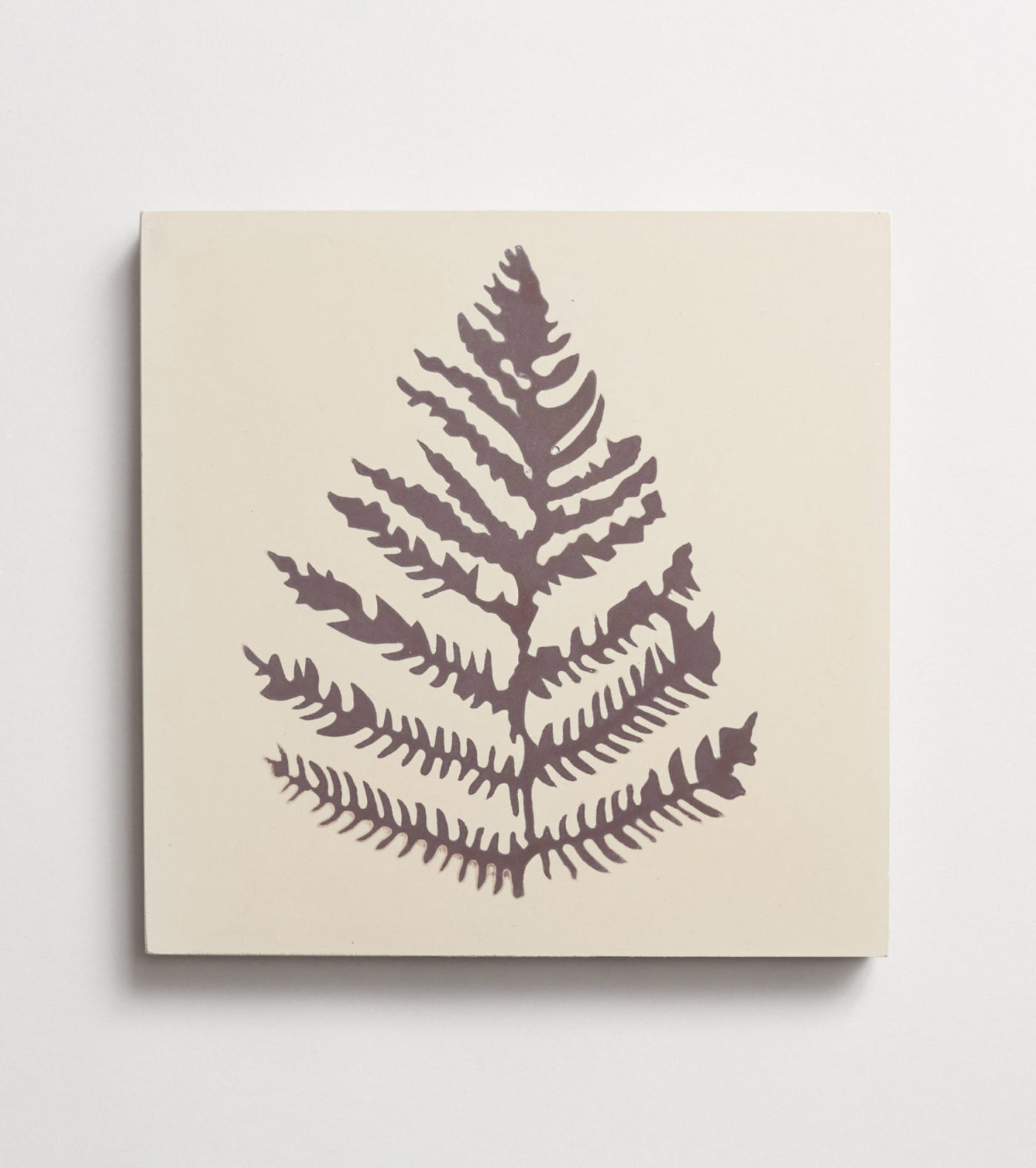 a fern leaf print on a square white tile.