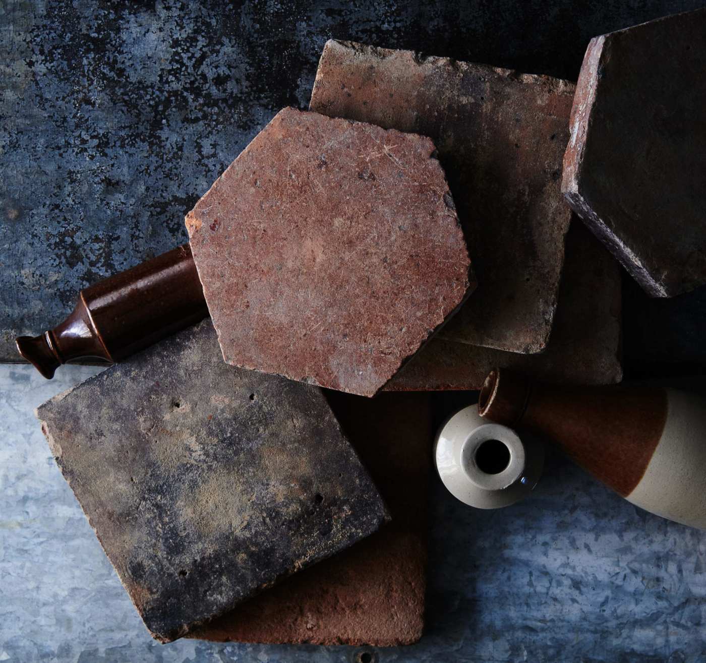 a set of terracotta tiles and vases on a dark surface.