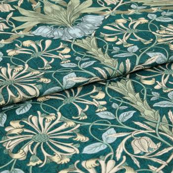Teal-green woven fabric with pale blue and cream floral vines; folded across the frame, displaying textured weave and layered petals; close-up view under soft diffuse light on a flat surface.