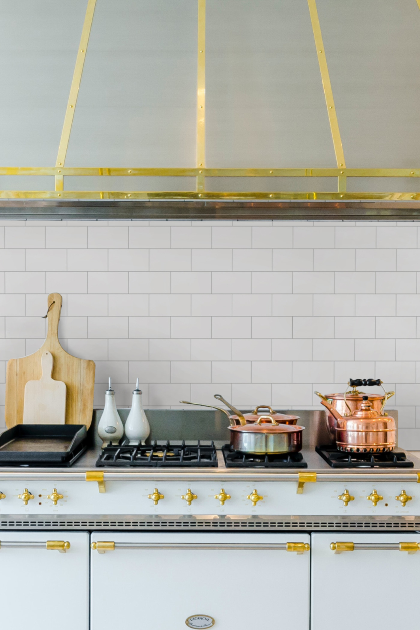 a white and gold kitchen with a stove and oven.