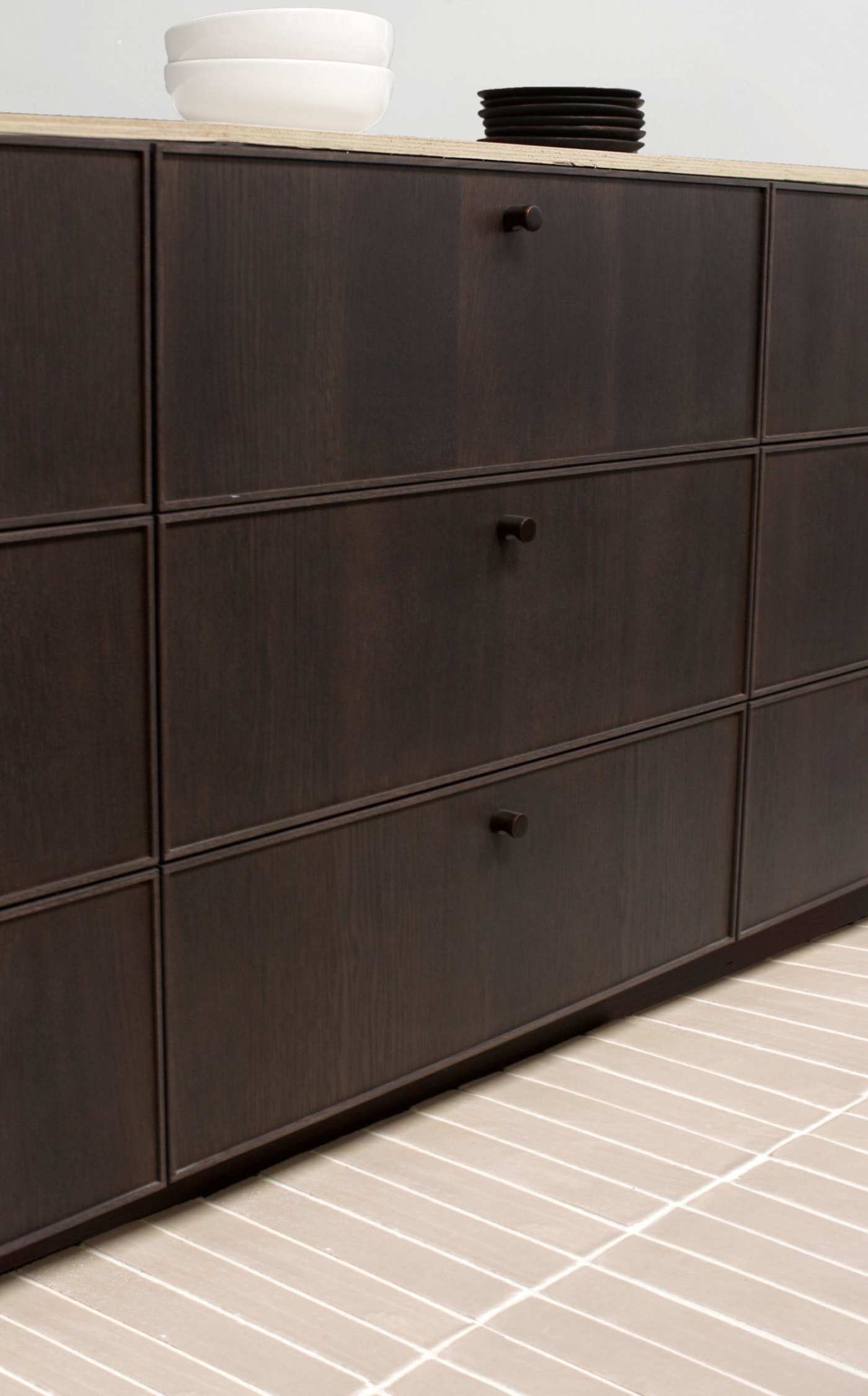 a dark brown dresser with drawers on a beige tile floor.