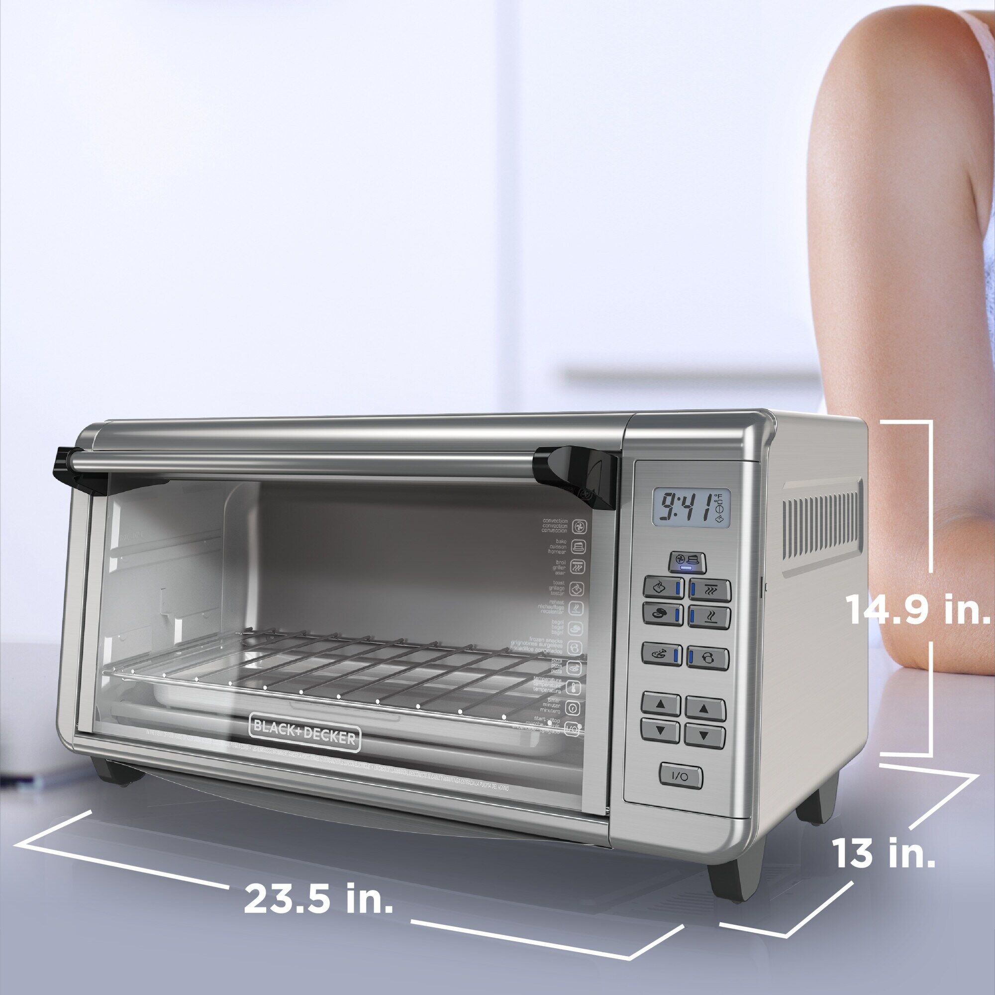 Image of BLACK+DECKER toaster oven on a kitchen counter near a man's arm. Drawn onto the image are the measurements of the unit.