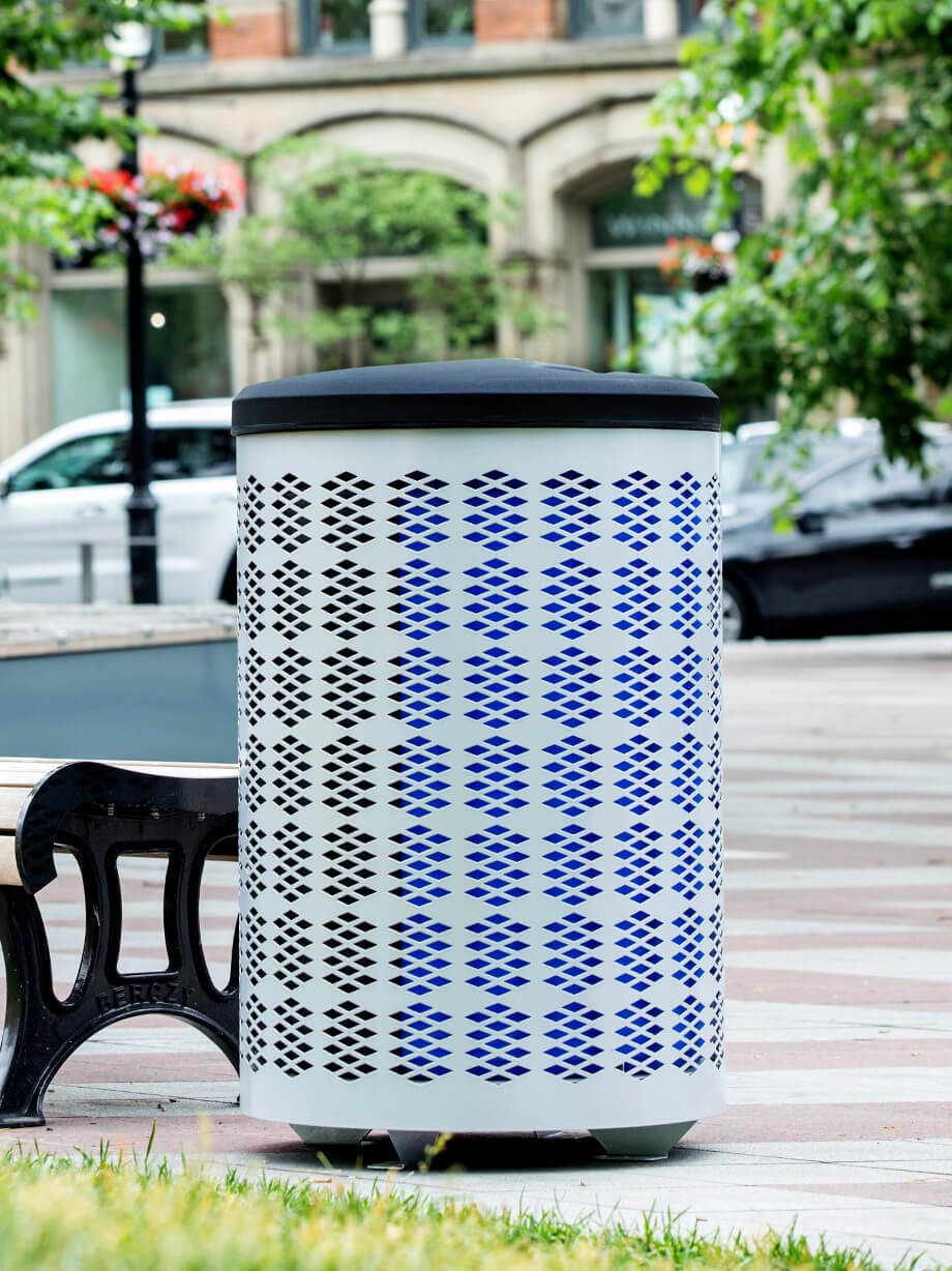 silver powder coated steel outdoor durable waste and recycling container with black plastic lid and restrictive openings in a municipal park area