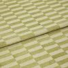 Folded green-and-cream checkered rug, raised pile squares forming a staggered grid; folded edge overlapping, displaying tufted texture and subtle wear in a close-up, evenly lit studio view.
