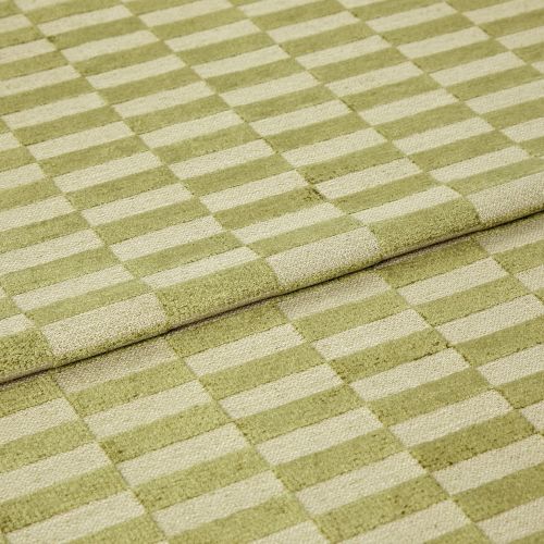 Folded green-and-cream checkered rug, raised pile squares forming a staggered grid; folded edge overlapping, displaying tufted texture and subtle wear in a close-up, evenly lit studio view.