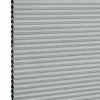 Light-gray honeycomb (cellular) blind, mounted vertically with narrow horizontal pleats and exposed hexagonal cells at the left edge; fully closed, filtering light; close-up view against a white background.