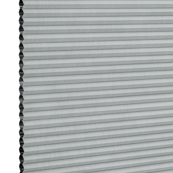Light-gray honeycomb (cellular) blind, mounted vertically with narrow horizontal pleats and exposed hexagonal cells at the left edge; fully closed, filtering light; close-up view against a white background.