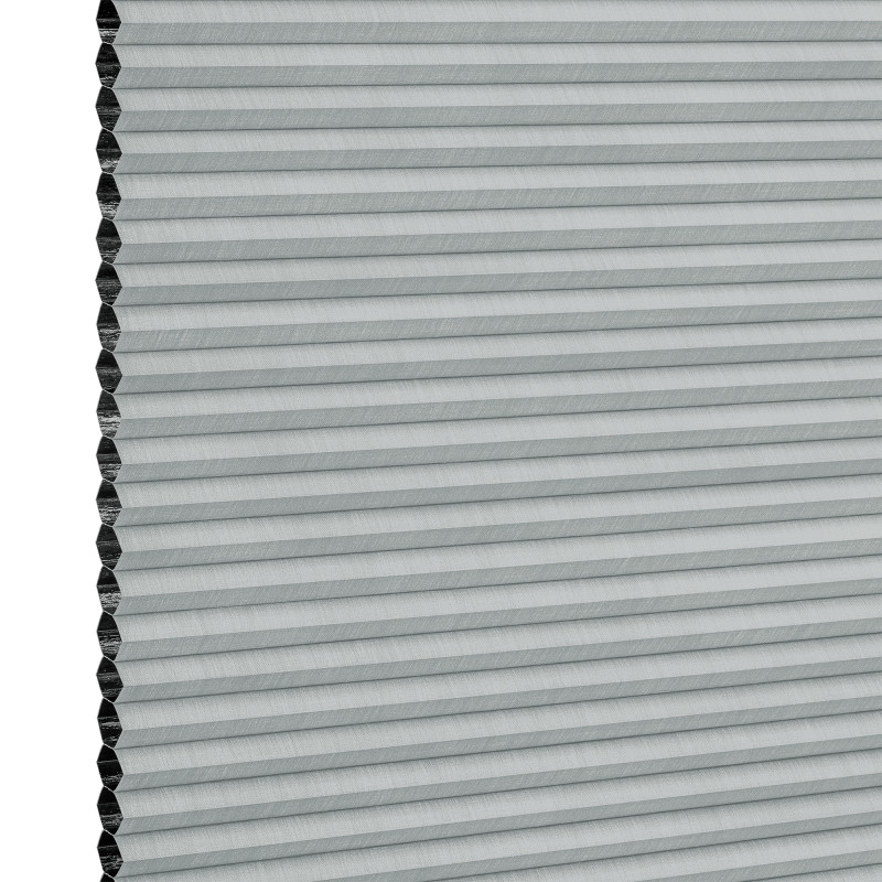 Light-gray honeycomb (cellular) blind, mounted vertically with narrow horizontal pleats and exposed hexagonal cells at the left edge; fully closed, filtering light; close-up view against a white background.