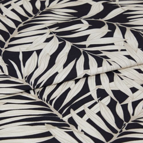 A folded decorative fabric with cream palm-leaf print on a black background; the layers overlap, emphasizing texture and weave, shown in a close-up under soft, even lighting.