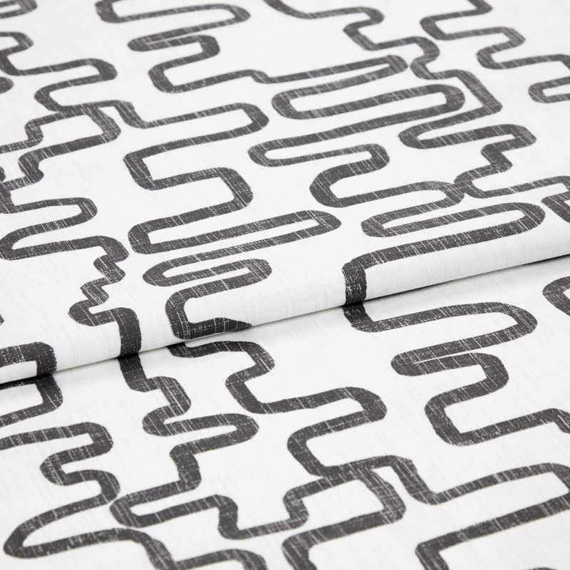 White woven fabric printed with charcoal, distressed looping-rectangle pattern, folded to show overlapping layers; studio close-up with even soft lighting and neutral background.