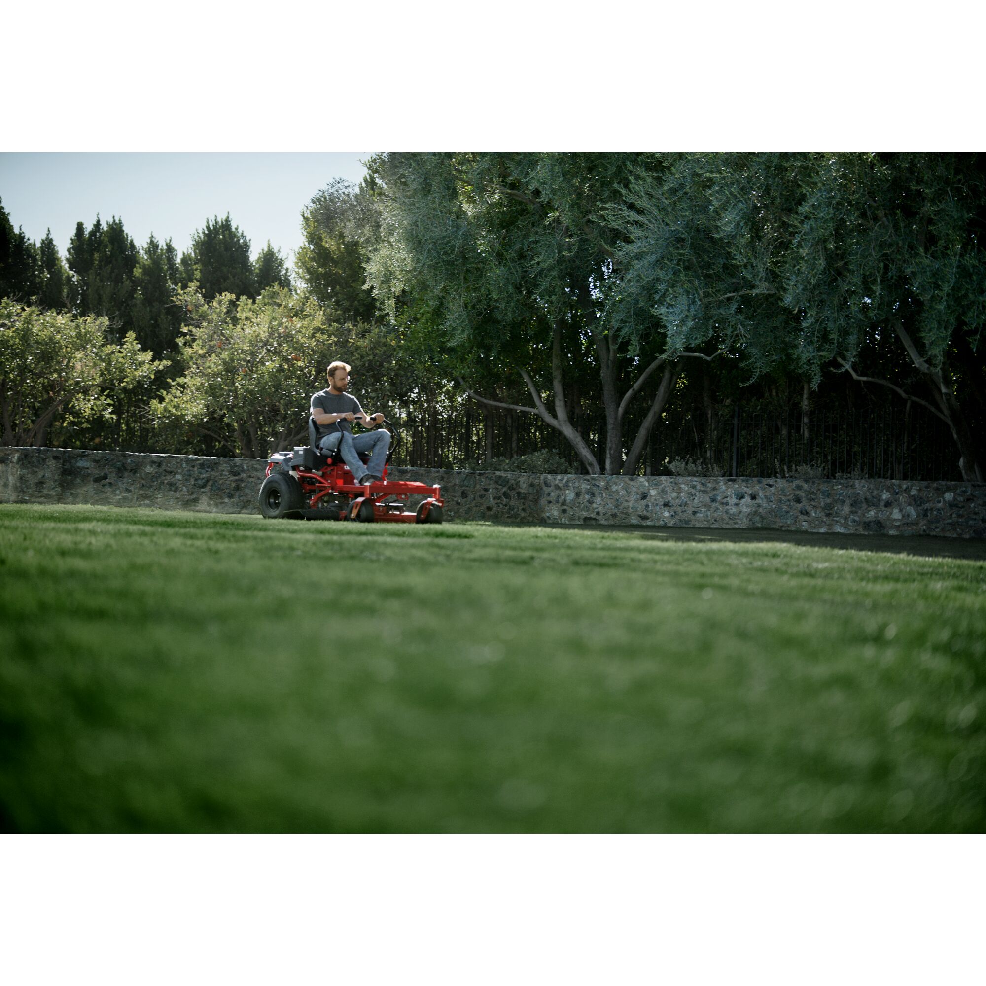 22 h p 46 inch zero turn riding mower being used by a person to mow the lawn.