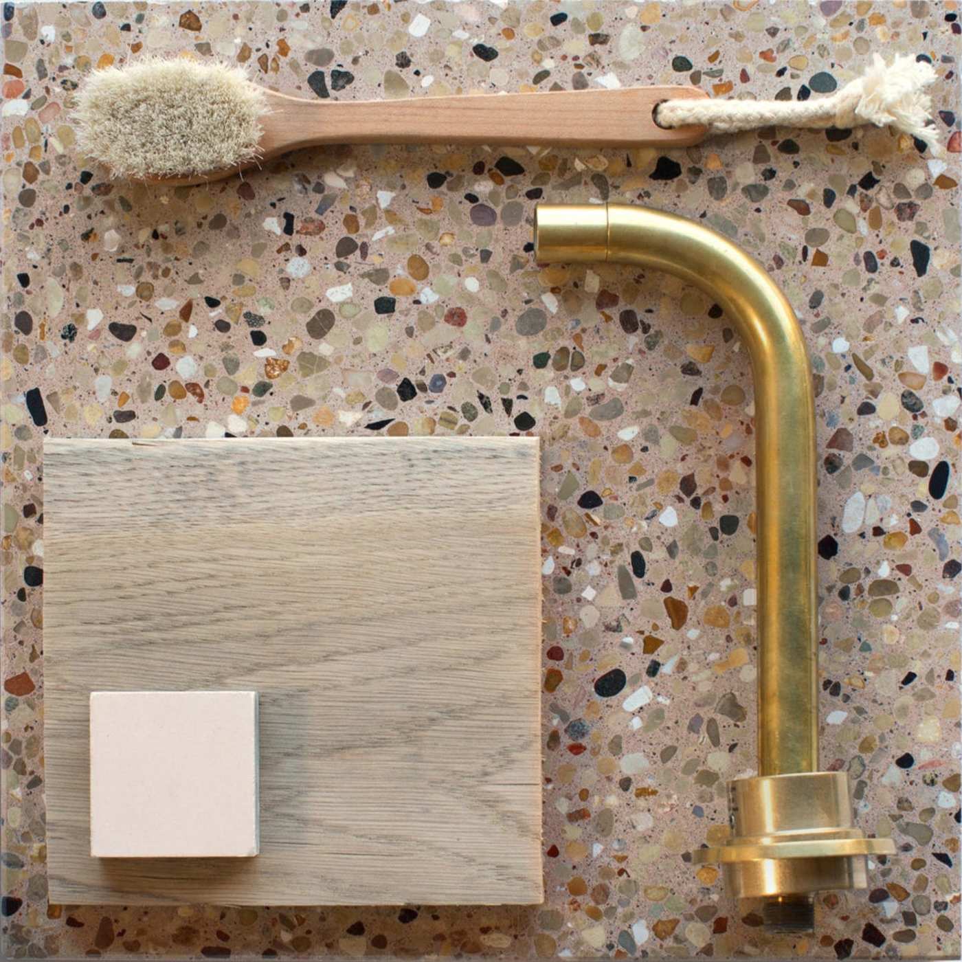 a bathroom with a brass faucet and brush on top of a stone countertop.