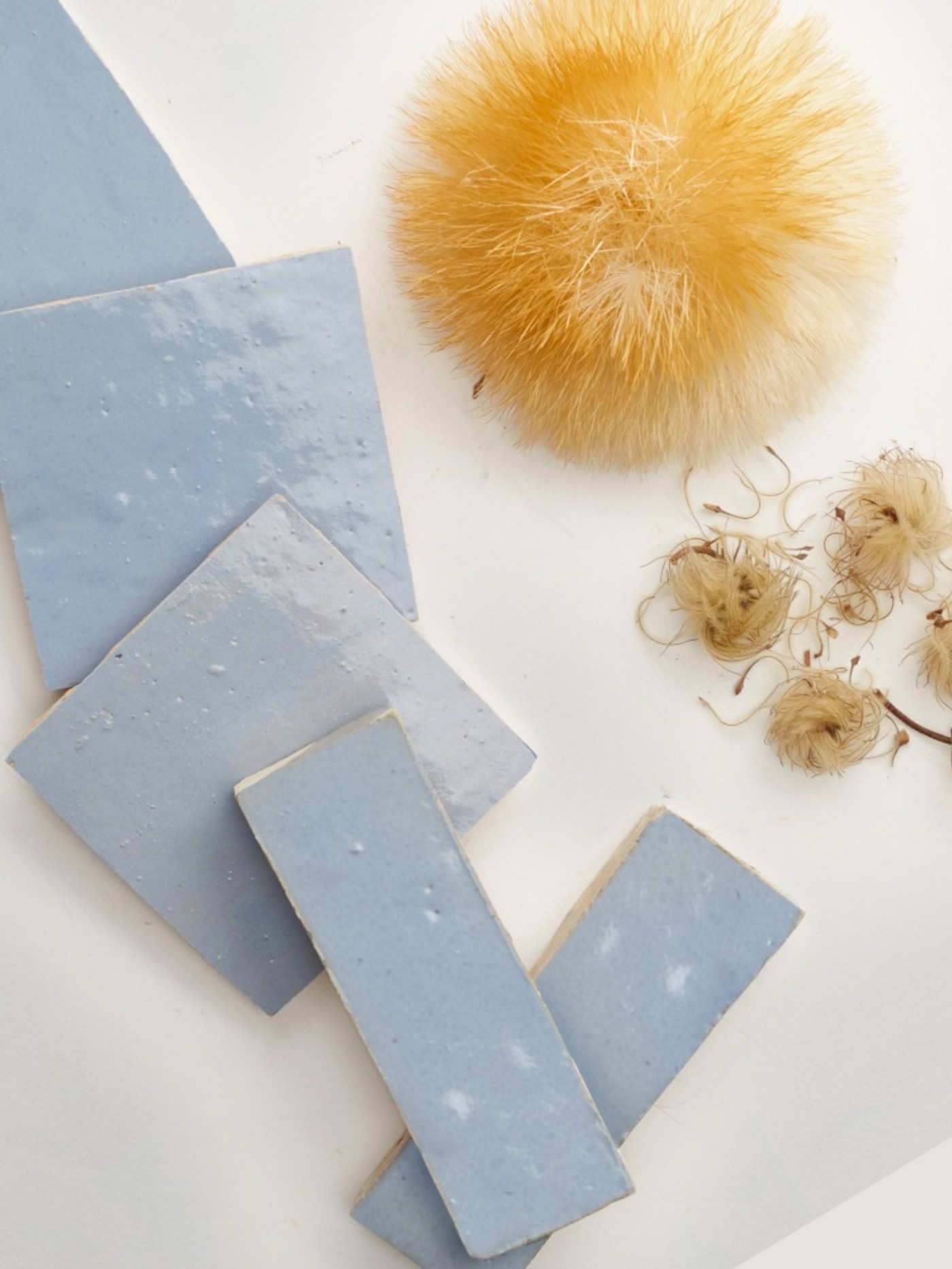 a white table with blue tiles and a dried plants.