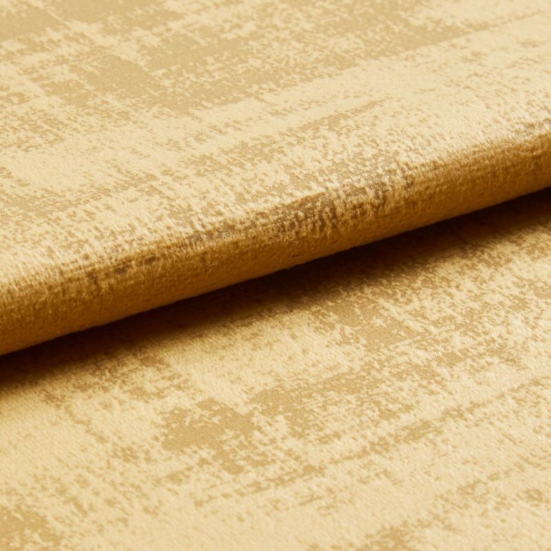 Crushed gold velvet fabric folded along an edge, showing mottled sheen and raised nap; close-up studio view with soft directional lighting.