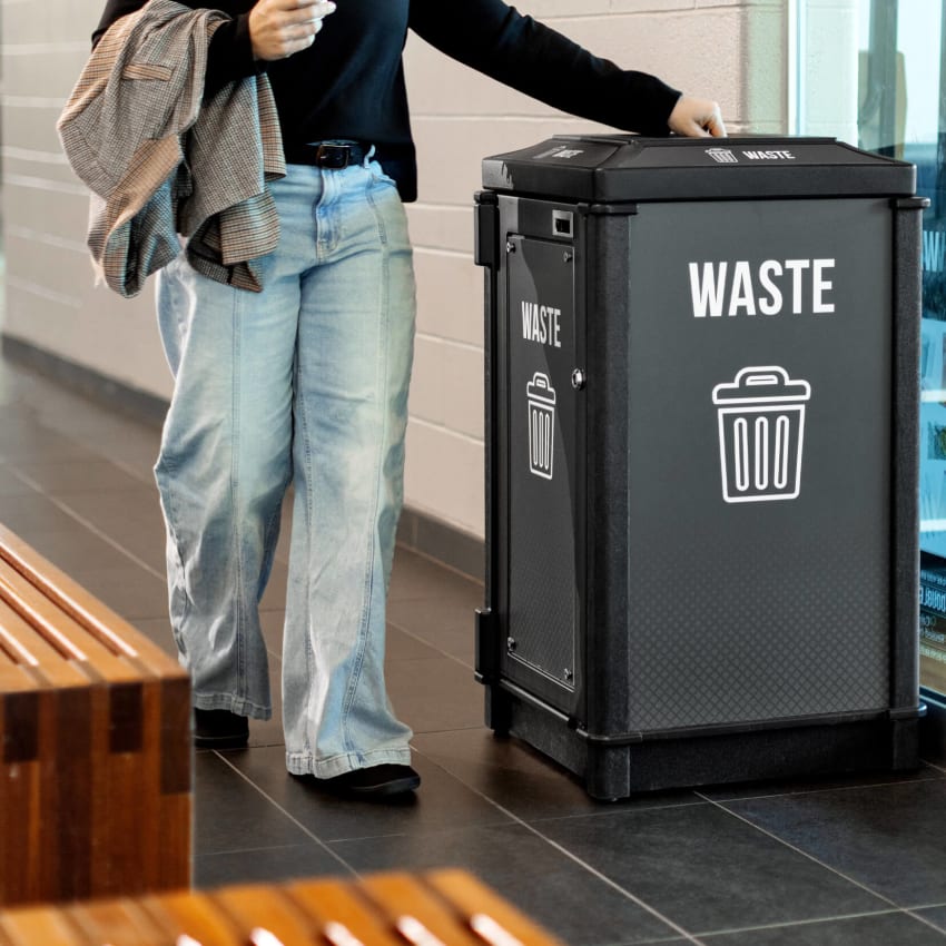 recycled plastic waste container inside with large bold body signs and labels for maximum waste diversion showing woman putting trash in bin