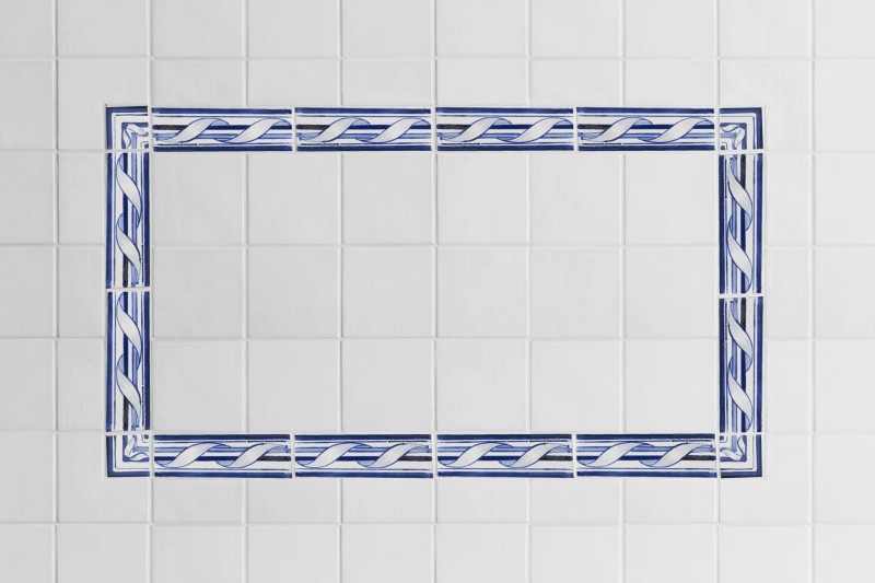 a blue and white tiled bathroom with a blue patterned border.