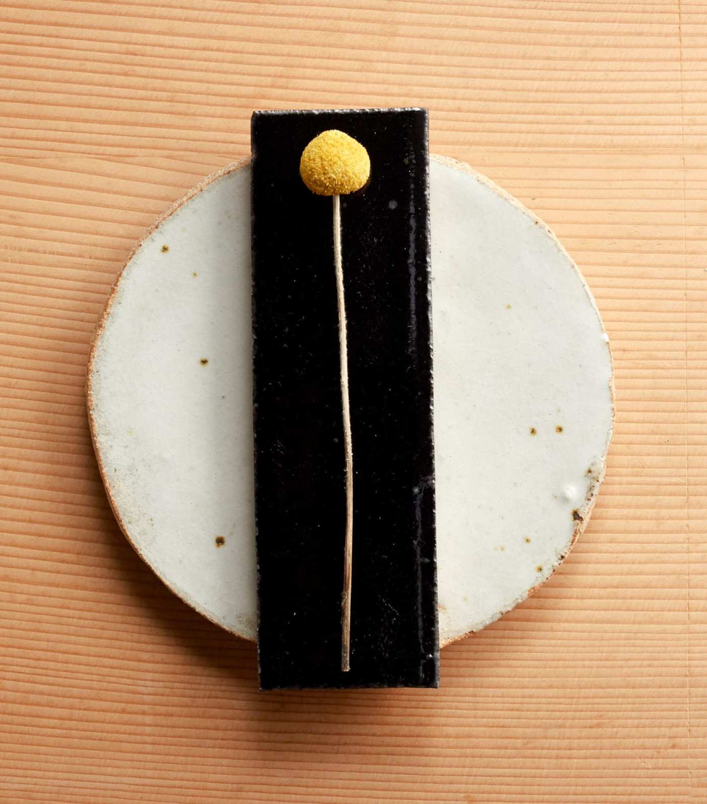 a black rectangle tile with a yellow flower on top.