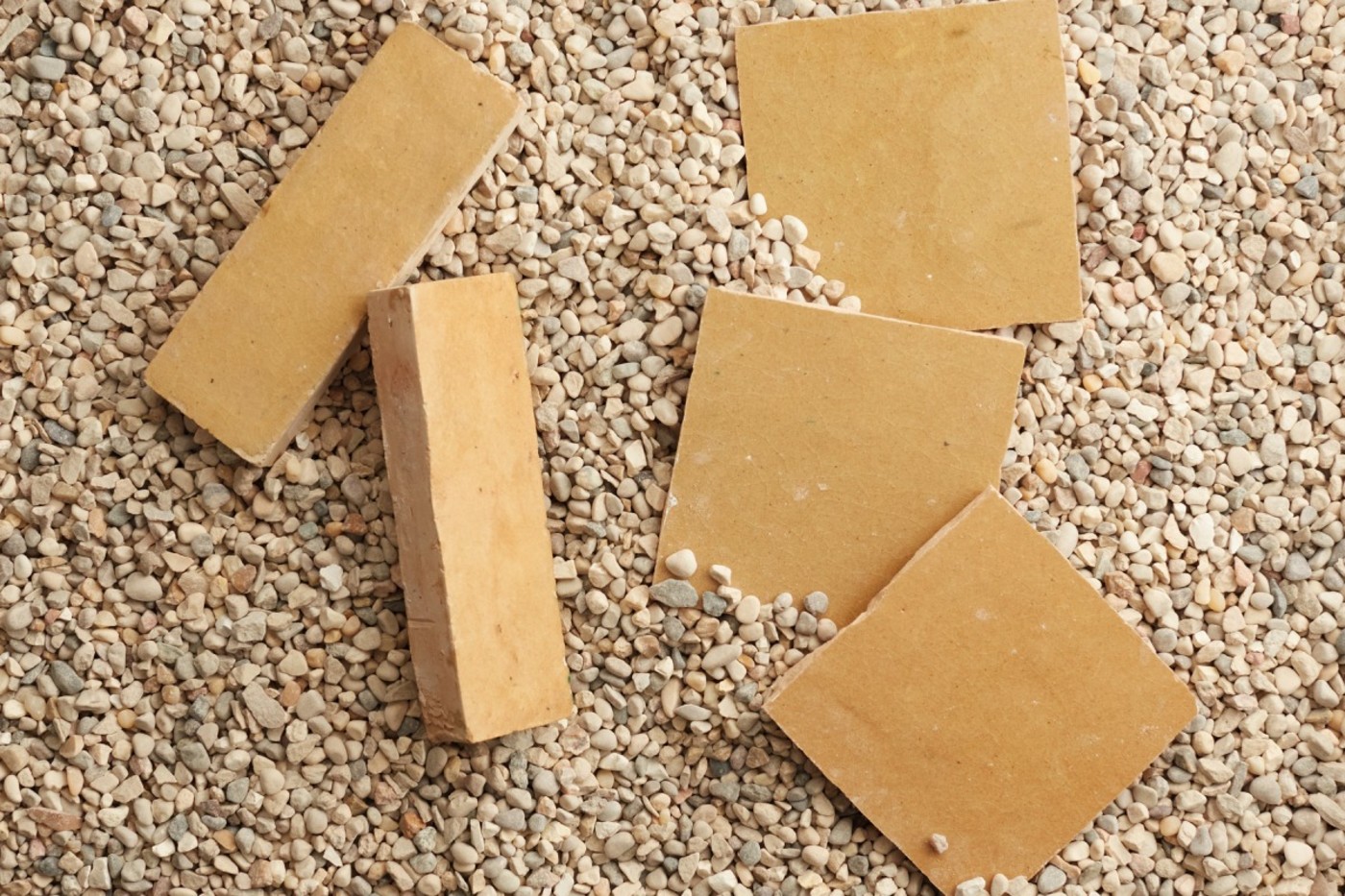 a group of yellow tiles on a gravel surface.