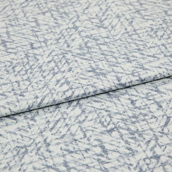 Light blue-and-white patterned fabric folded once, overlapping; textured woven surface with irregular, fern-like striations, photographed close-up under even studio lighting.