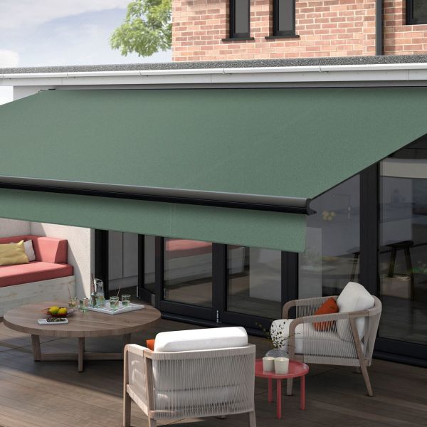 Green fabric retractable awning mounted above glass doors, extended with black roller and front bar, shading a wooden patio with lounge seating, round table, and brick-backed house in daylight.