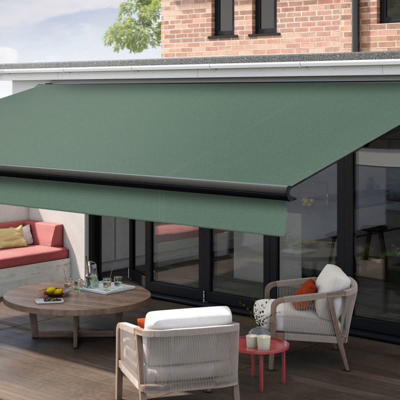 Green fabric retractable awning mounted above glass doors, extended with black roller and front bar, shading a wooden patio with lounge seating, round table, and brick-backed house in daylight.