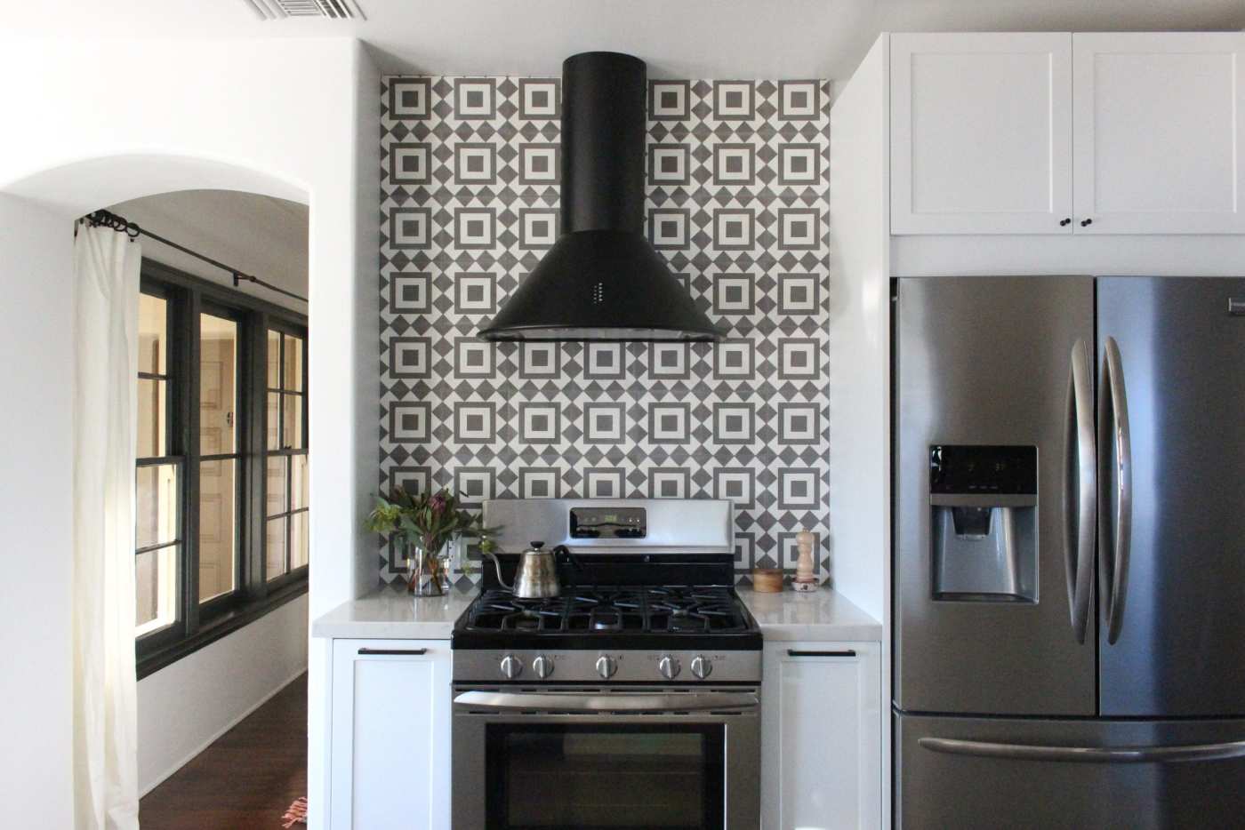 a kitchen with a black and white tiled stove backsplash.