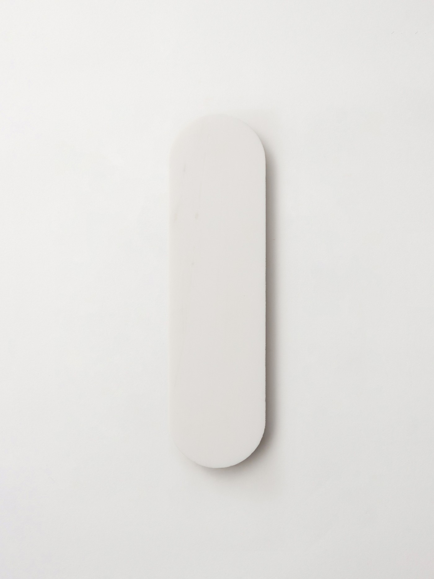 a white oval tile on a white surface.