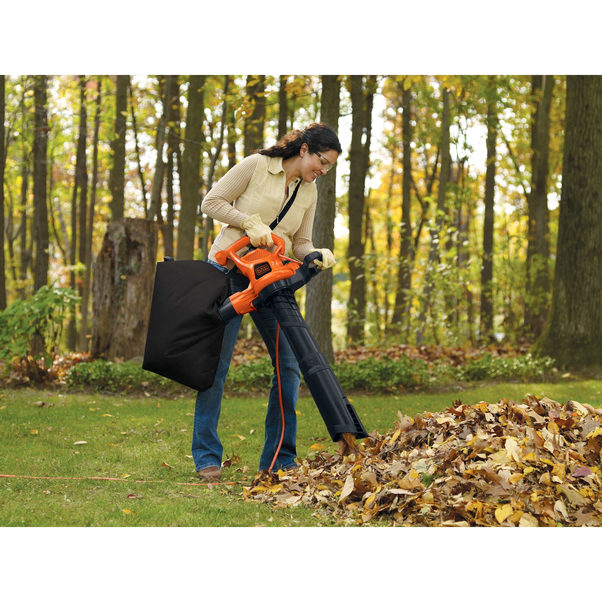 12 Ampere blower vacuum mulcher being used by a person to clean leaf debris.