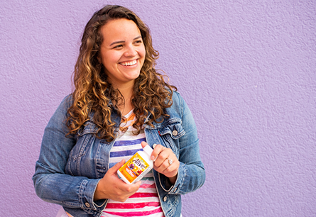 Woman smiling and holding bottle of Alive Adult Ultra Potency Multivitamins. 