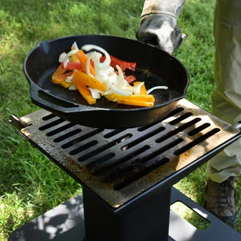 Photo of food being cooked in a cast iron skillet over a Watchman grill.